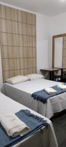 2 letti posti in una stanza con specchio di Hotel Chalé Centro a Curvelo Altre 159 foto