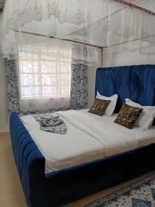 a bed with a blue headboard and pillows on it at Greenstar villa homes in Kisii