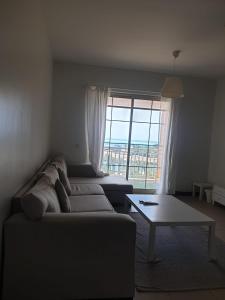 een woonkamer met een bank, een tafel en een raam bij زهور المدينة in King Abdullah Economic City