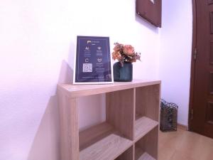 ein Bücherregal mit einem Bild und Blumen darauf in der Unterkunft Caparica Escape By Gt House in Costa da Caparica