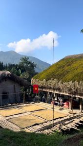eine Hütte mit einem Grasdach, auf dem eine Flagge prangte in der Unterkunft Ha Giang Plateau Travel - Tours & Motorbikes Rental - Cao Nguyen Hotel in Ha Giang