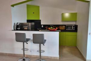 a kitchen with green cabinets and a counter with two stools at Studio moderne près de Capesterre-Belle-Eau avec piscine in Capesterre-Belle-Eau