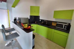 a kitchen with green cabinets and a bowl of fruit on a counter at Studio moderne près de Capesterre-Belle-Eau avec piscine in Capesterre-Belle-Eau