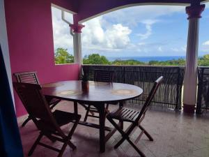 a table and chairs on a balcony with a view of the ocean at Appartement avec vue mer à Capesterre-Belle-Eau in Capesterre-Belle-Eau