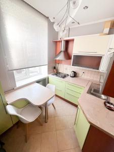 uma cozinha com armários verdes e uma mesa e cadeiras em Central City Puskin Street em Chişinău