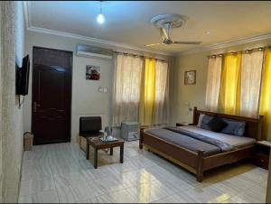 a bedroom with a bed and a table and yellow curtains at Home from Home Ghana in Accra