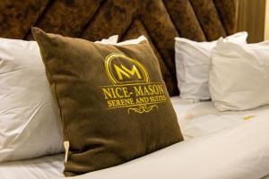 a pillow sitting on top of a bed with white pillows at Nice-mason Serene and Suites in Benin City