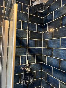 a shower with a blue tiled wall in a bathroom at Delightful 1 Bedroom Cottage in Buxton +12 photos