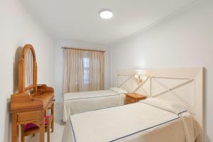 1 Schlafzimmer mit 2 Betten, einer Kommode und einem Spiegel in der Unterkunft Playa Delphin 205 in Puerto Naos