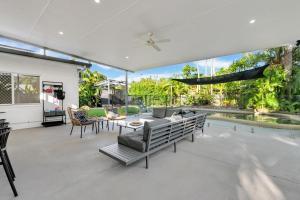 a patio with a couch and chairs and a pool at Eden House Kewarra Beach in Kewarra Beach