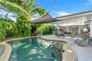 an indoor swimming pool with a hammock in a house at Eden House Kewarra Beach in Kewarra Beach