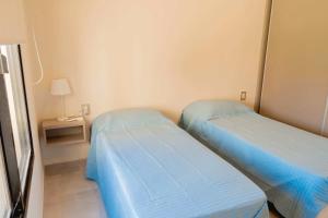 zwei Betten in einem kleinen Zimmer mit einer Lampe in der Unterkunft Casabella total confort y relax in Villa Elisa