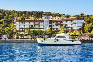 una barca bianca in acqua di fronte a un edificio di Princes' Palace Resort, Buyukada - Member of The Leading Hotels of the World a Adalar