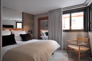 ein Schlafzimmer mit zwei Betten, einem Stuhl und einem Fenster in der Unterkunft La Résidence Belledonne in Courchevel