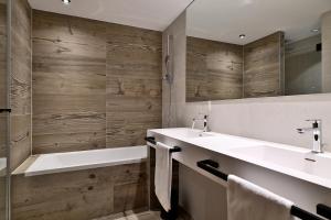 ein Badezimmer mit Waschbecken, Badewanne und Spiegel in der Unterkunft La Résidence Belledonne in Courchevel + 40 Fotos
