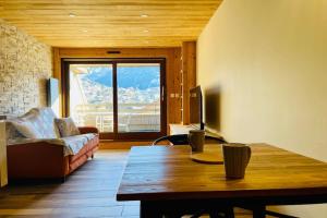 Una sala de estar con una mesa, un sofá y un televisor. en Beautiful studio with magnificent view, en Briançon