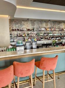 un bar con sedie arancioni di fronte a un bancone di Stunning Apartment in Ellipse Waterfall Midrand a Midrand