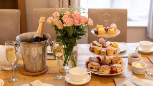 a table with plates of pastries and a vase of flowers at Teagles Cottage in Stow, EV parking in Stow on the Wold