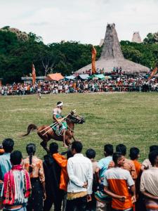 a person riding a horse in front of a crowd of people at Pemimpi Sumba in Lambatama