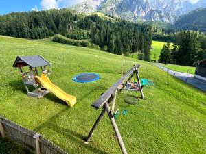 a playground with a slide and a playset in a field at Badmeisterhof in Leogang