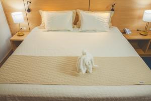 a small white statue sitting on a bed at Grande Hotel Guarapuava in Guarapuava +55 photos