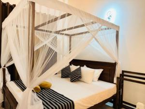 a bedroom with a canopy bed with black and white pillows at Sunset Villa in Dickwella