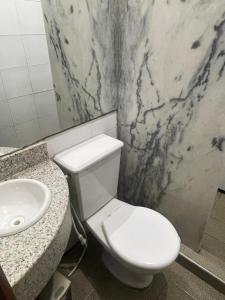a bathroom with a white toilet and a sink at Pousada Casa Bali in Fortaleza