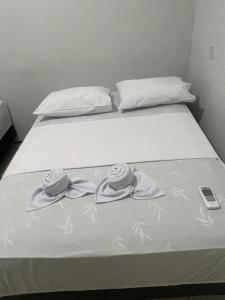 a bed with two towels and a cell phone on it at Pousada Casa Bali in Fortaleza