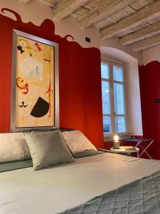 ein Schlafzimmer mit roten Wänden und einem Bett mit einem Gemälde in der Unterkunft Loggiato Tassis Charme&Relax in Bergamo