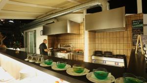 a man in a kitchen with green bowls on a counter at Apartamentos Río Piedras in Puerto Rico de Gran Canaria