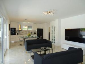 a living room with a couch and a tv and a kitchen at More i Sol Rab Pool House in Rab