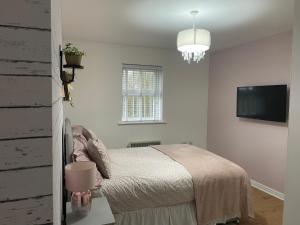 een witte slaapkamer met een bed en een televisie bij Double room with en-suite in Halton