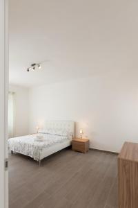 een witte slaapkamer met een bed en een houten vloer bij ArtStay Apt Humanitas, Two Rooms, Parking in Rozzano