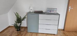 a white dresser with a lamp and a plant at stilvolles Apartment für 4 Personen in Ulmerfeld in Ulmerfeld +1 photo
