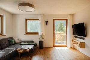 een woonkamer met een bank en een televisie bij New Opening Penthouse Zirm in Selva dei Molini
