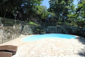 einen Pool mit einer Steinmauer und einem Zaun in der Unterkunft Chácara in Mairiporã - São Paulo in Mairiporã