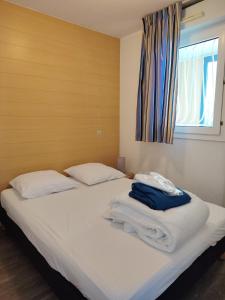 een slaapkamer met twee bedden met witte lakens en een raam bij Les Hauts de Balaruc in Balaruc-les-Bains