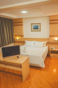 a bedroom with a bed and a desk with a computer at Grande Hotel Guarapuava in Guarapuava