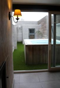 een uitzicht op een tuin met een jacuzzi door een raam bij La vie en Roos in Maldegem