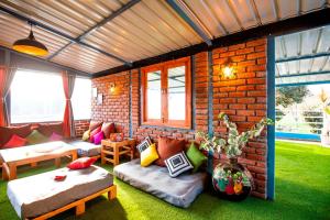 a room with a brick wall with a couch and tables at PACK Mukteshwar in Mukteshwar