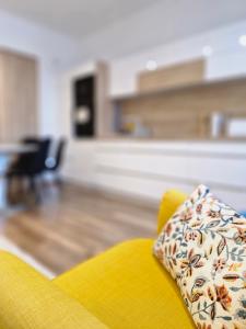 een gele bank met een kussen erop in de woonkamer bij Várker39 Apartman in Sopron +36 foto's