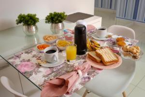 a breakfast table with breakfast foods and coffee and orange juice at Motel Fascínio (Only Adults) in Cascavel