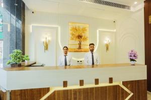 two men are standing at a reception desk at Hotel Ginger Palace Delhi Airport in New Delhi