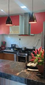 a kitchen with red walls and a counter with flowers on it at Casa Praia Cotijuba in Belém
