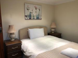 a bedroom with a bed and two night stands with lamps at The Annexe at the Cedars in South Brent