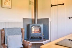 a wood burning stove in a room with a chair at Host and Stay - Florence in Aylsham +13 photos