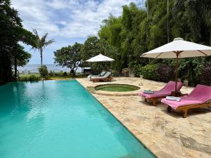une piscine avec deux chaises et un parasol dans l'établissement Beachfront Villa Nirwana with Private Jacuzzi, à Pengastulan