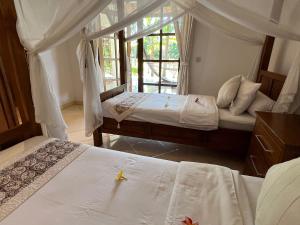 een slaapkamer met twee bedden en een raam bij Beachfront Villa Nirwana with Private Jacuzzi in Pengastulan