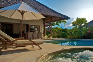 une chaise et un parasol à côté de la piscine dans l'établissement Beachfront Villa Nirwana with Private Jacuzzi, à Pengastulan