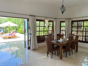een eetkamer met een houten tafel en stoelen bij Beachfront Villa Nirwana with Private Jacuzzi in Pengastulan